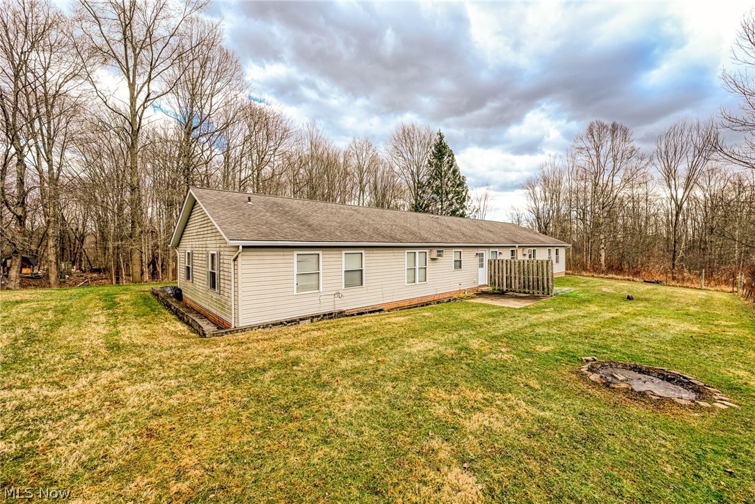 8464-8446 Tallmadge Road Diamond, OH 44412 - Photo 24 of 39 Back of house featuring a shingled roof, a yard, and view of scattered trees