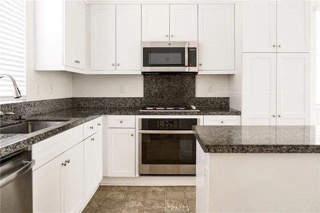 a kitchen with stainless steel appliances granite countertop a stove a microwave and a white cabinets