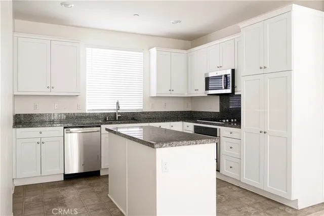 a kitchen with granite countertop white cabinets sink and white appliances