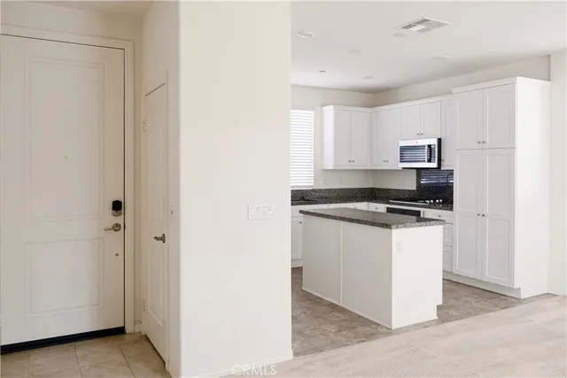 a kitchen with granite countertop white cabinets and black appliances