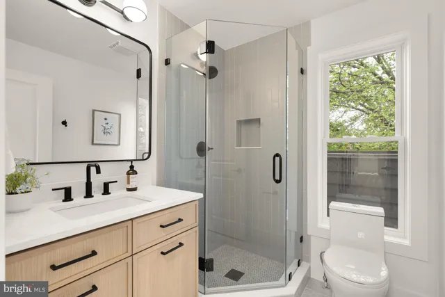 a bathroom with a shower sink vanity mirror and toilet