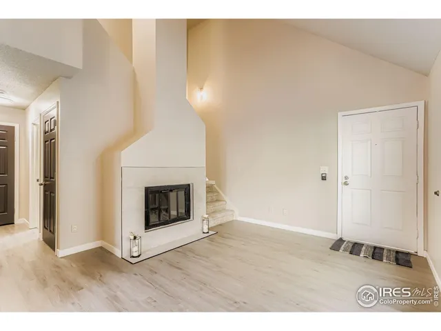 a view of an empty room with wooden floor and a fireplace