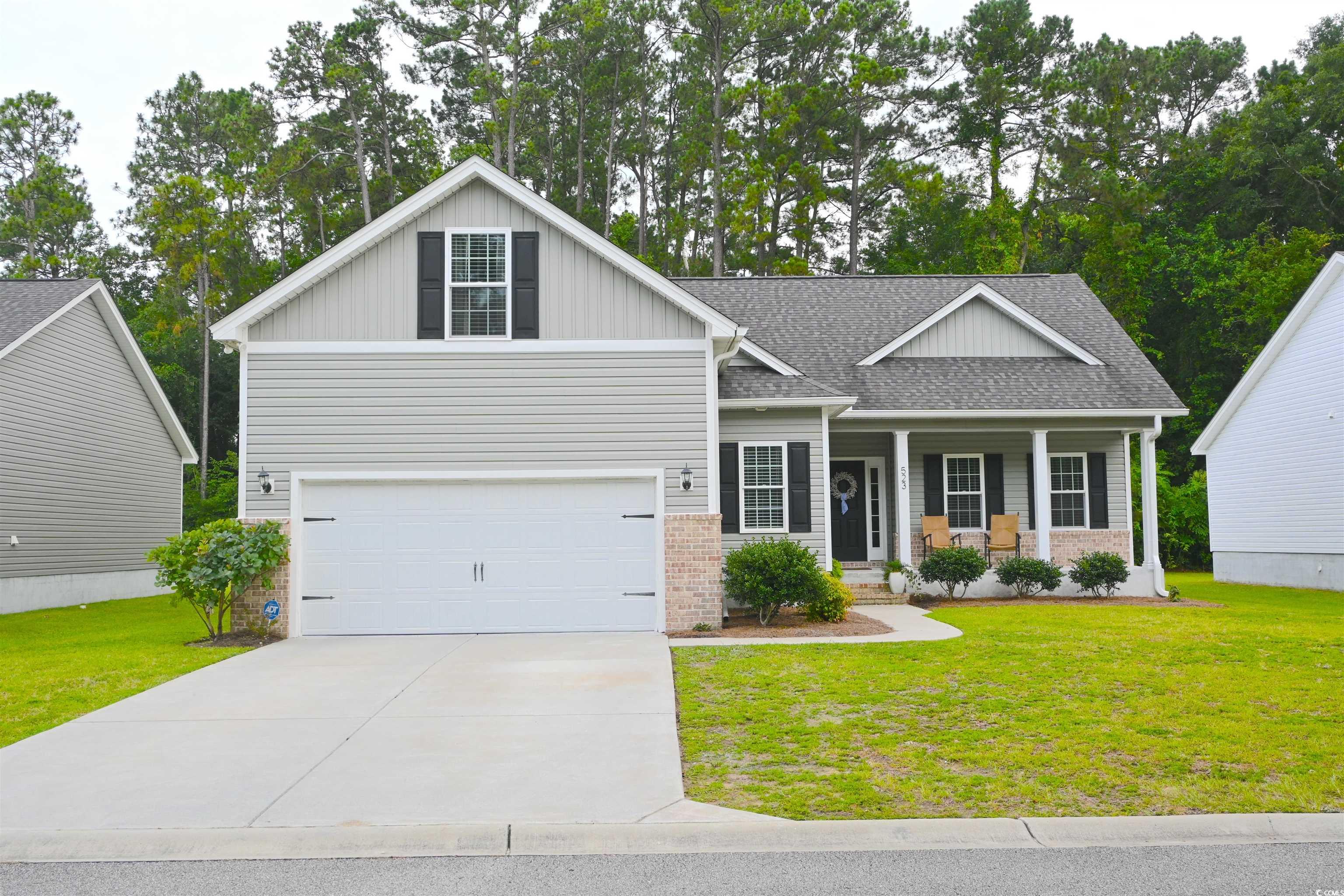 View of front of house with a porch, a garage, a front lawn, and driveway