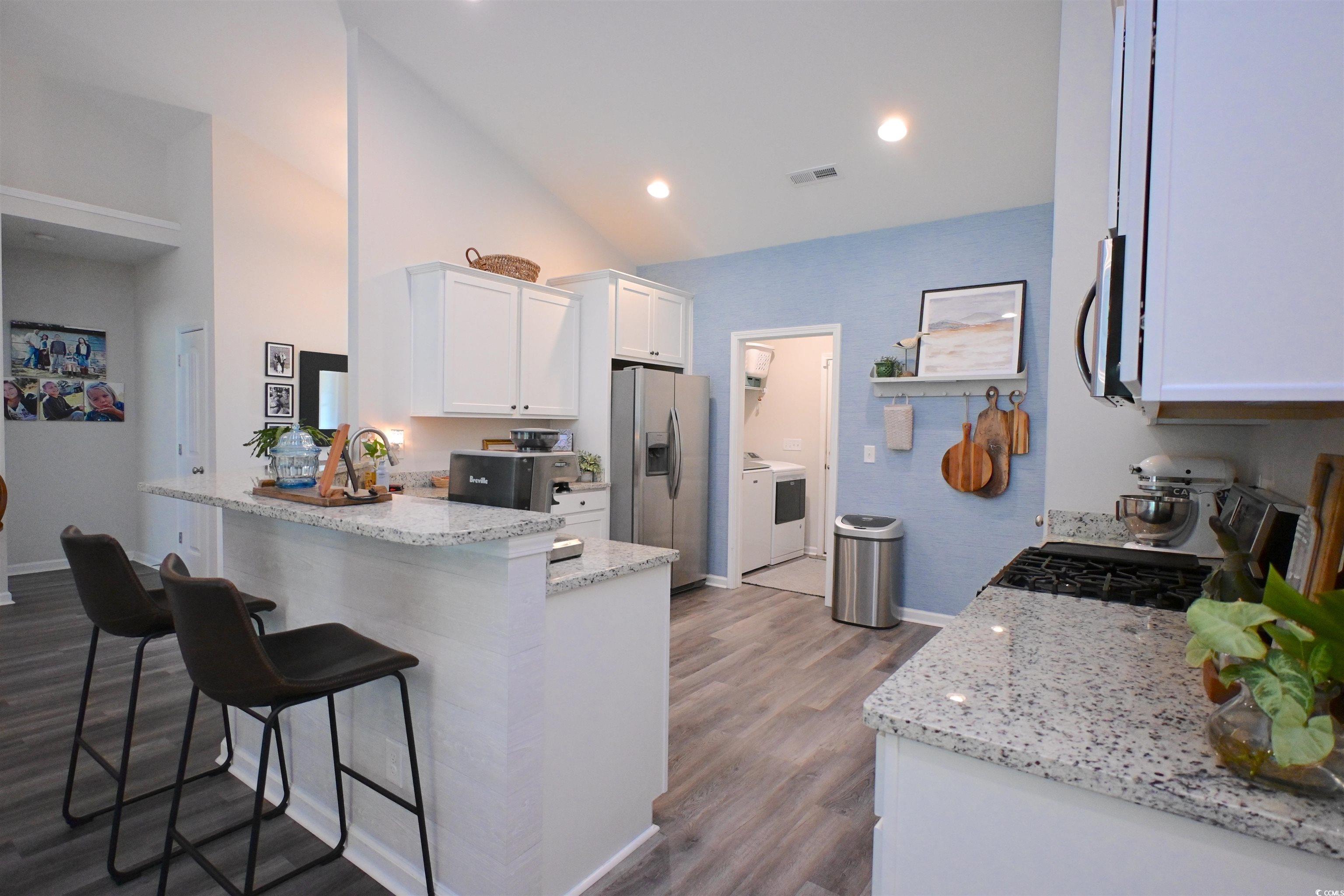 523 Charlton Boulevard Georgetown, SC 29440 - Photo 7 of 33 Kitchen featuring appliances with stainless steel finishes, white cabinets, a kitchen breakfast bar, washer / dryer