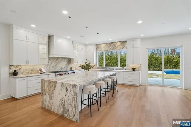 a kitchen with stainless steel appliances granite countertop a stove a sink a refrigerator and a dining table with wooden floor