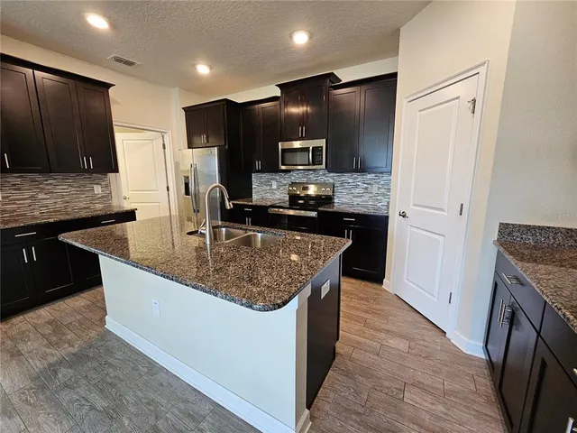 a kitchen with kitchen island granite countertop stainless steel appliances a sink stove and refrigerator