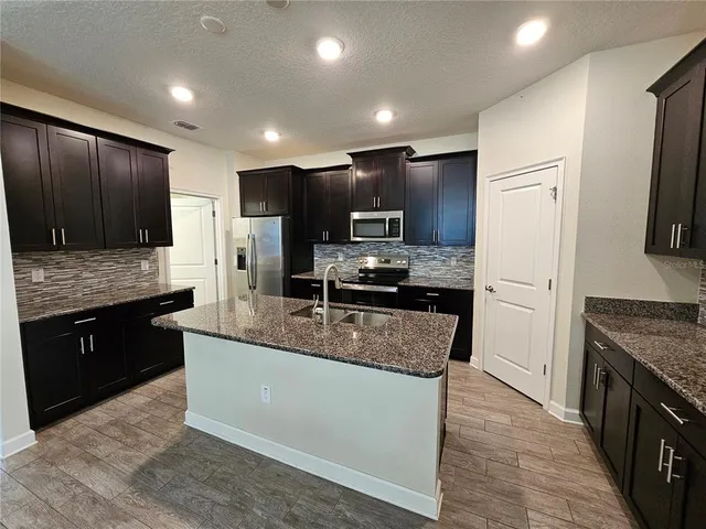 a large kitchen with granite countertop a large counter top stainless steel appliances and cabinets