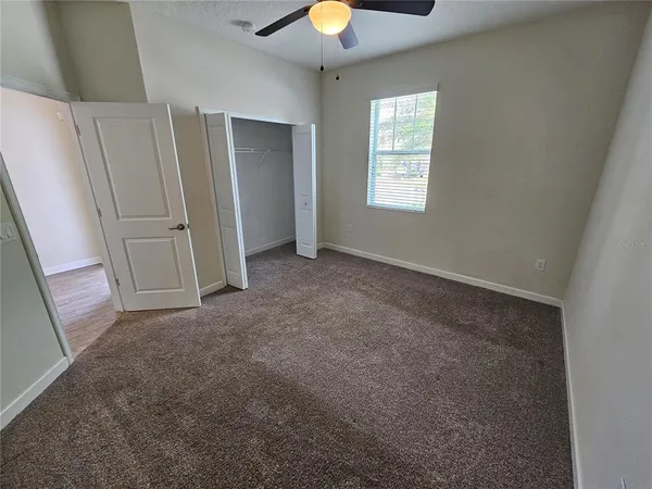 an empty room with a window and chandelier fan