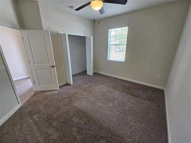 an empty room with a window and chandelier fan