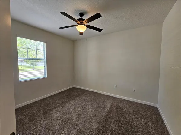 an empty room with a window and a fan