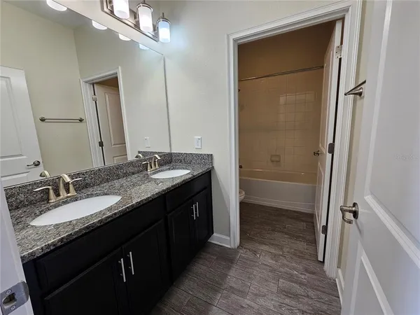 a bathroom with a granite countertop sink a mirror and a shower