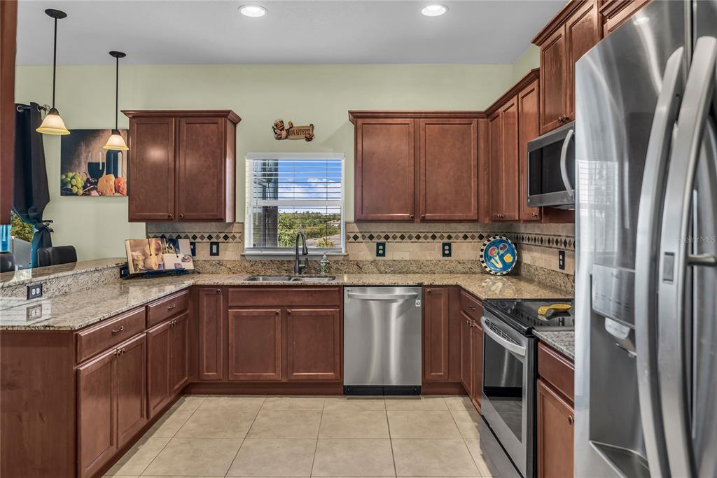 2962 Inca Avenue Clermont, FL 34715 - Photo 12 of 55 a kitchen with stainless steel appliances granite countertop a refrigerator and a stove top oven
