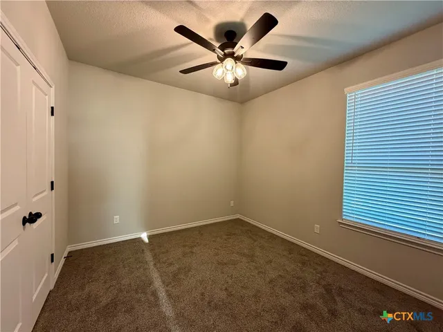 an empty room with ceiling fan and window
