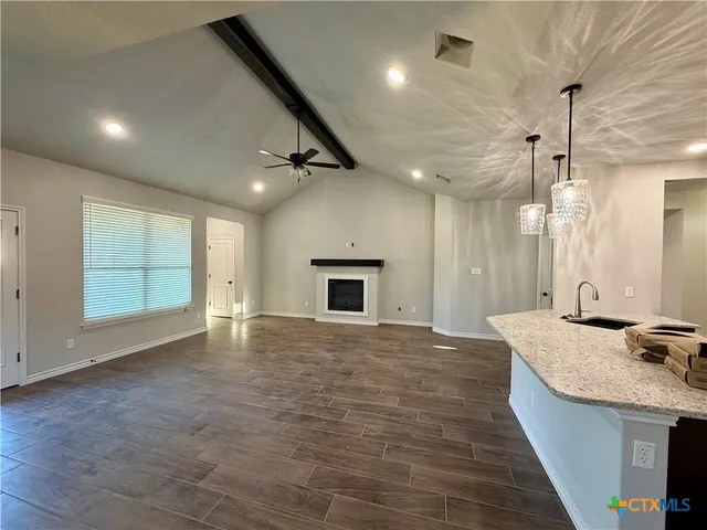 a view of an empty room with a kitchen and a window