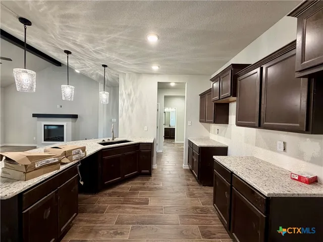 a large kitchen with granite countertop a sink and cabinets