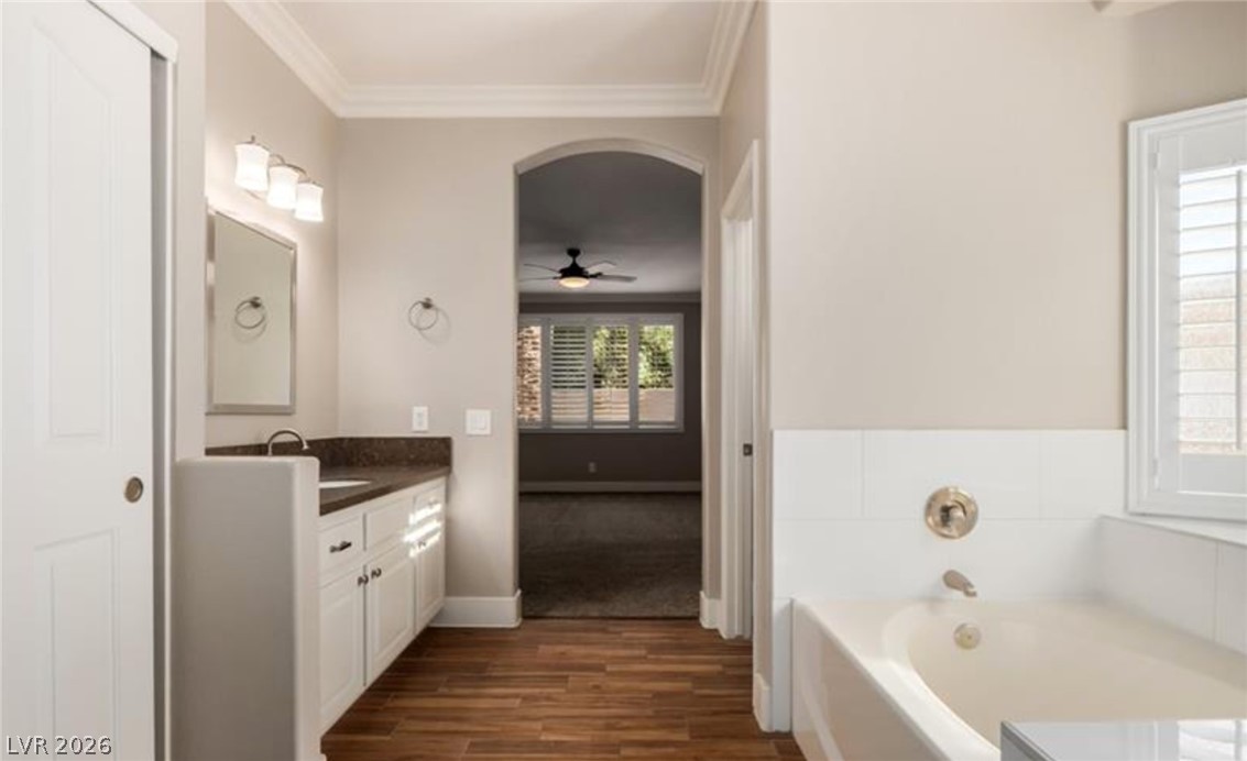 264 Pointe Ranier Avenue Henderson, NV 89012 - Photo 23 of 43 A well-appointed bathroom offers a vanity with ample counter space and a classic tub, with a glimpse into an adjacent carpeted room.