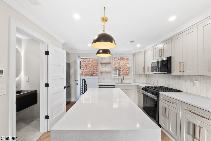 1453 Morris Avenue Union, NJ 07083 - Photo 24 of 48 a kitchen with stainless steel appliances a refrigerator a stove a sink dishwasher and white cabinets with wooden floor