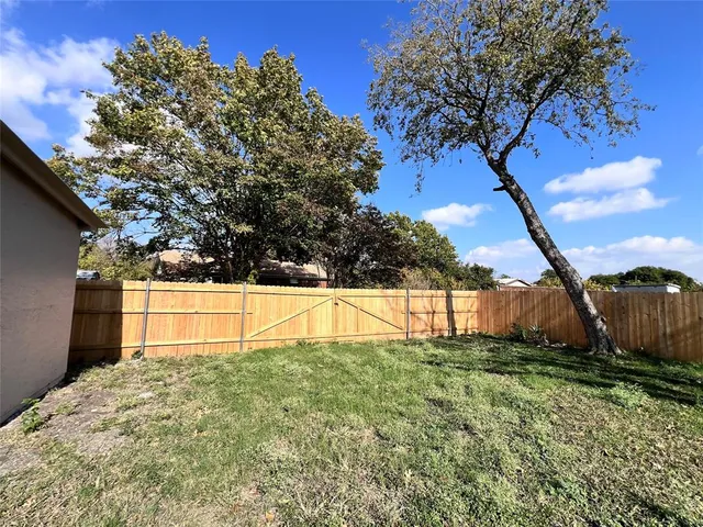 a view of backyard with large tree and wooden fence