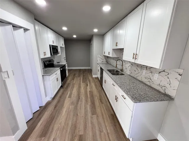 a kitchen with granite countertop a sink stove and refrigerator