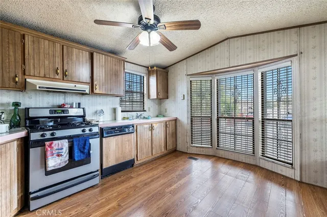 a kitchen with stainless steel appliances granite countertop a stove a sink dishwasher and a refrigerator with wooden floor