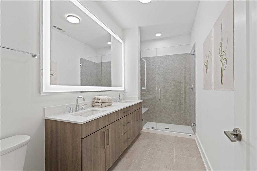 775 Juniper Street Northeast, Unit 227 Atlanta, GA 30308 - Photo 16 of 42 a bathroom with a double vanity sink toilet and shower