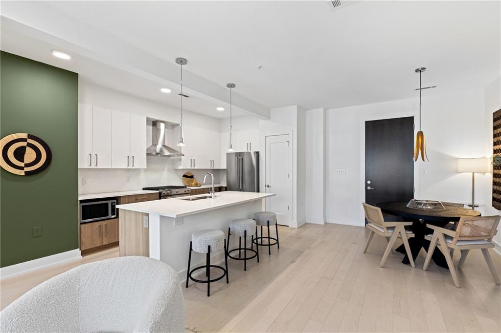 775 Juniper Street Northeast, Unit 227 Atlanta, GA 30308 - Photo 3 of 42 a kitchen with stainless steel appliances kitchen island a table chairs in it and white cabinets