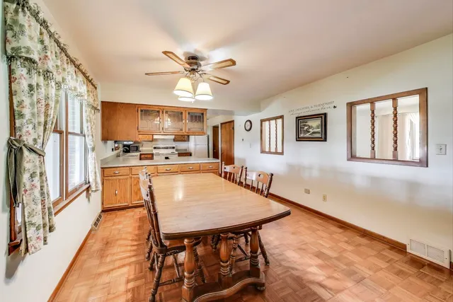 a dining room with stainless steel appliances kitchen island granite countertop a refrigerator a stove a microwave oven with a dining table and chairs with wooden floor