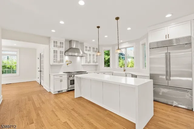 a large white kitchen with lots of counter space wooden floor and stainless steel appliances