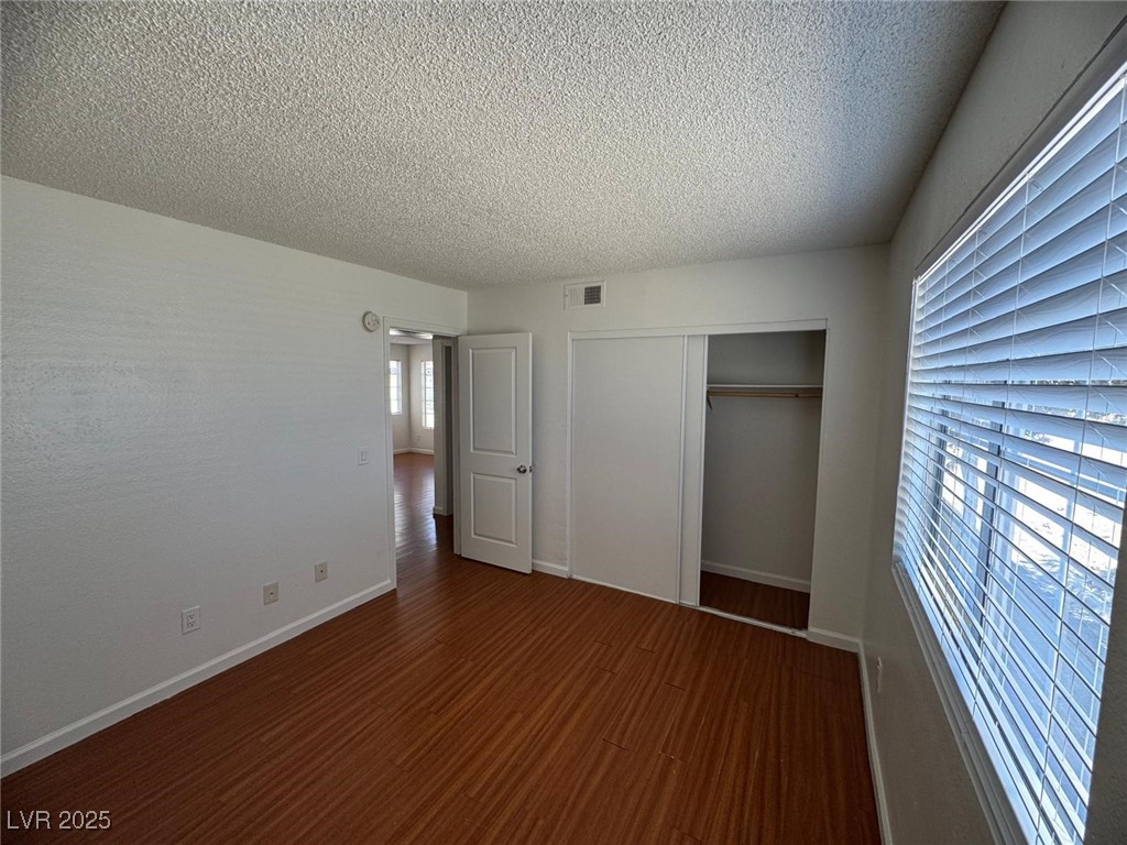 2732 Alicialynn Way, Unit A Las Vegas, NV 89121 - Photo 11 of 14 Unfurnished bedroom featuring a textured ceiling, a closet, wood finished floors, and baseboards