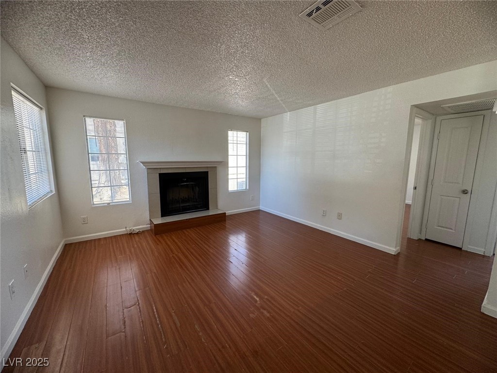 2732 Alicialynn Way, Unit A Las Vegas, NV 89121 - Photo 2 of 14 Unfurnished living room with a textured ceiling, dark wood-style flooring, a tiled fireplace, and baseboards