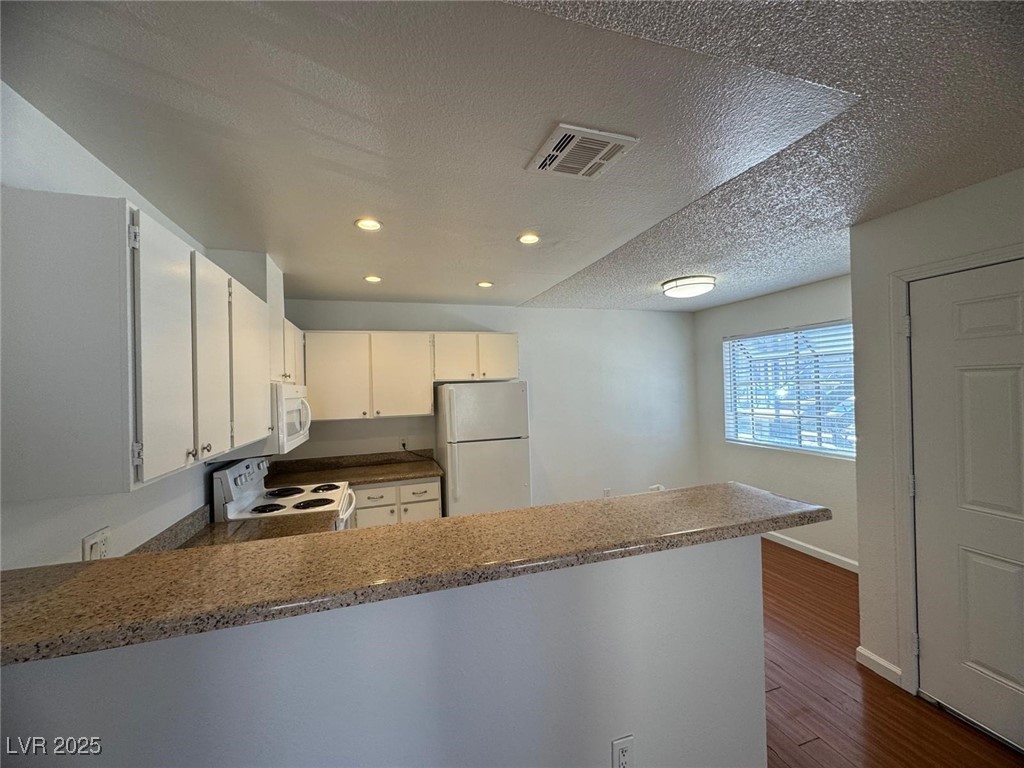 2732 Alicialynn Way, Unit A Las Vegas, NV 89121 - Photo 4 of 14 Kitchen with white appliances, a peninsula, a textured ceiling, dark wood-type flooring, and recessed lighting