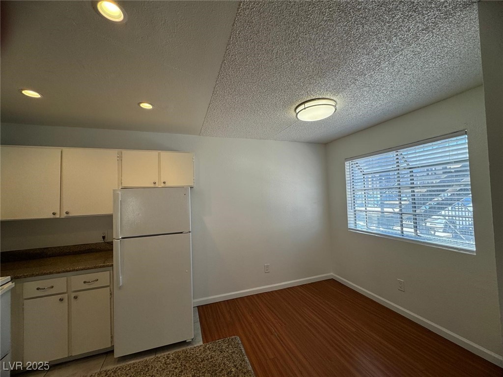 2732 Alicialynn Way, Unit A Las Vegas, NV 89121 - Photo 8 of 14 Kitchen featuring white appliances, white cabinets, wood finished floors, a textured ceiling, and baseboards