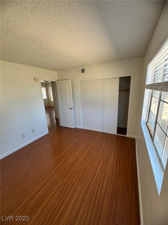 2732 Alicialynn Way, Unit A Las Vegas, NV 89121 - Photo 9 of 14 Unfurnished bedroom featuring a textured ceiling, dark wood-type flooring, a closet, and baseboards