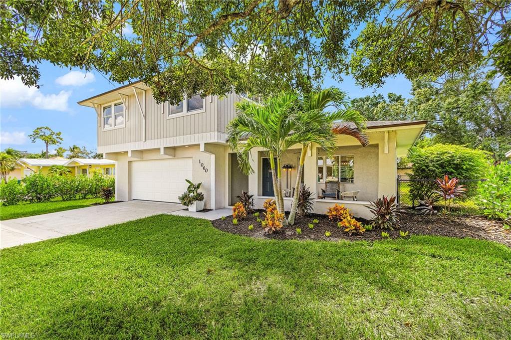 View of front of home with an attached garage, driveway, stucco siding, and covered porch