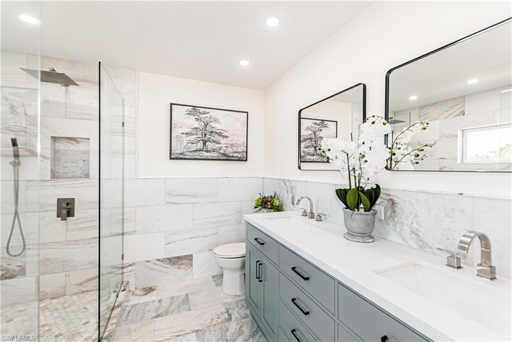 1060 Cooper Drive Naples, FL 34103 - Photo 5 of 7 Bathroom with double vanity, a marble finish shower, tile walls, recessed lighting, and a wainscoted wall