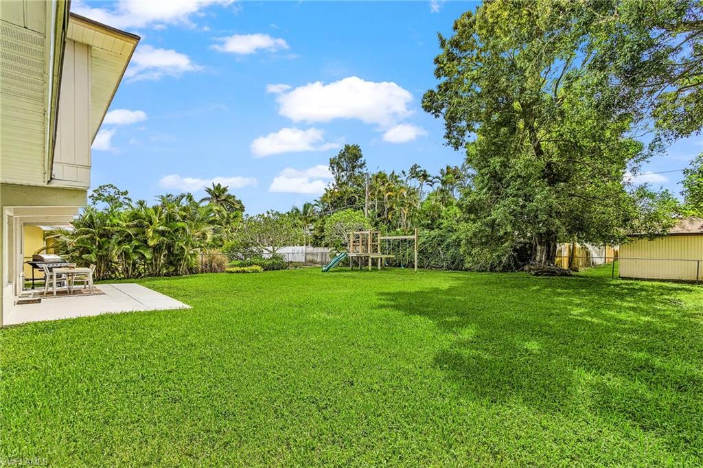 1060 Cooper Drive Naples, FL 34103 - Photo 6 of 7 Fenced backyard with a playground and a patio area