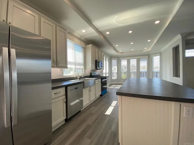 a kitchen with stainless steel appliances granite countertop a refrigerator a sink dishwasher a stove and a refrigerator with wooden floor