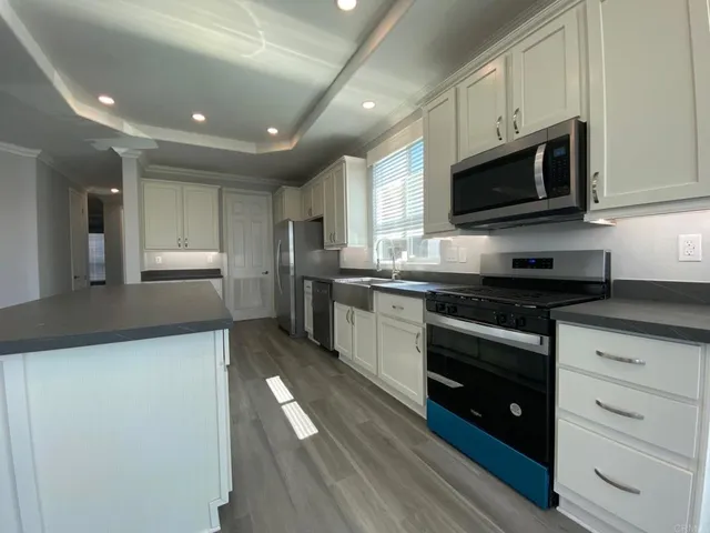 a kitchen with stainless steel appliances granite countertop a stove a sink and a microwave