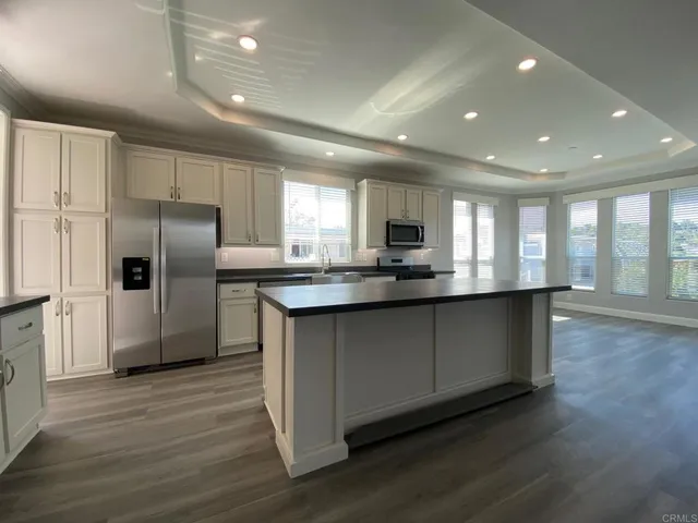 a kitchen with stainless steel appliances granite countertop a refrigerator a sink dishwasher a stove and a refrigerator with wooden floor