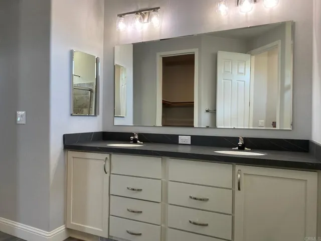 a bathroom with a granite countertop sink and a mirror