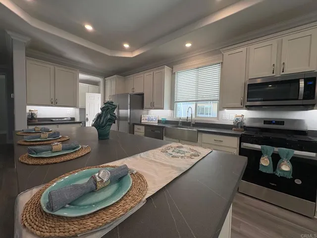 a kitchen with stainless steel appliances granite countertop a sink a stove a microwave a refrigerator and cabinets