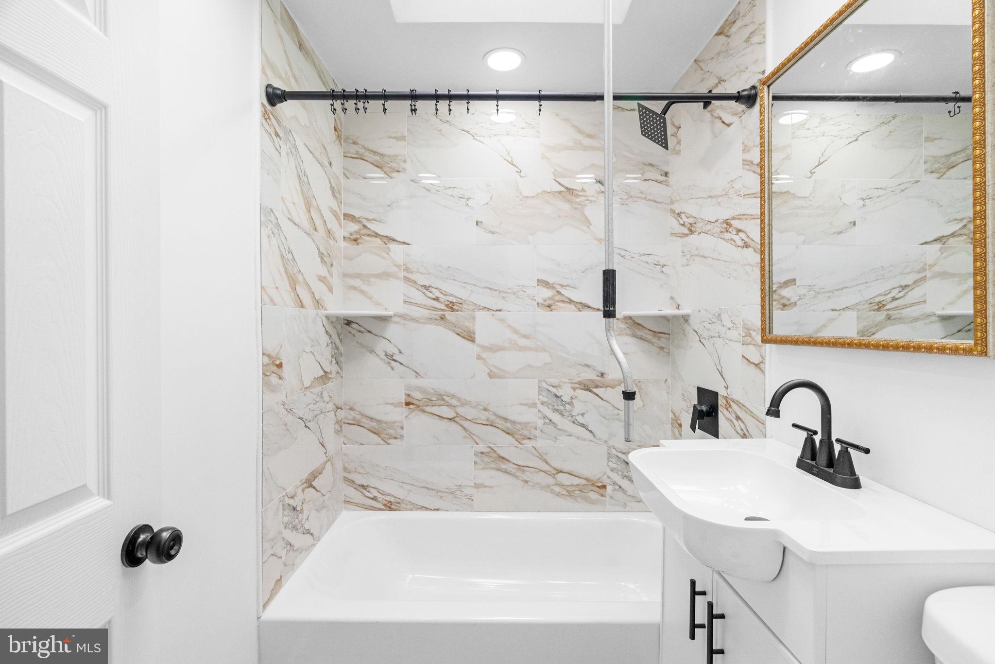 7703 Gilbert Street Philadelphia, PA 19150 - Photo 27 of 37 a bathroom with a sink and mirror with bathtub