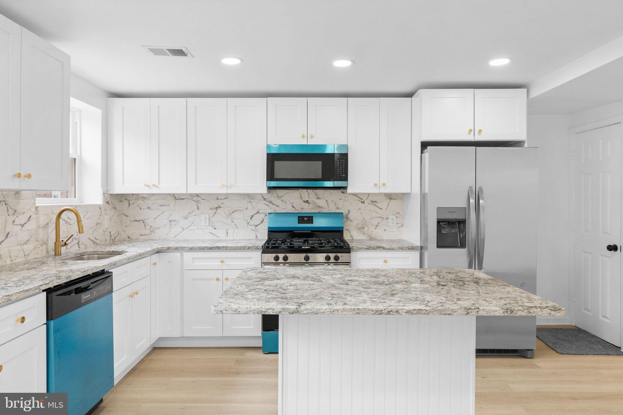 7703 Gilbert Street Philadelphia, PA 19150 - Photo 7 of 37 a kitchen with kitchen island granite countertop stainless steel appliances a sink stove and refrigerator