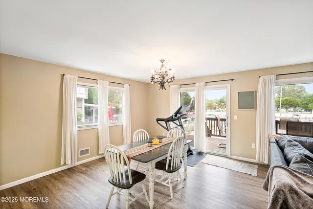 a kitchen with stainless steel appliances granite countertop a refrigerator a stove a sink and white cabinets with wooden floor