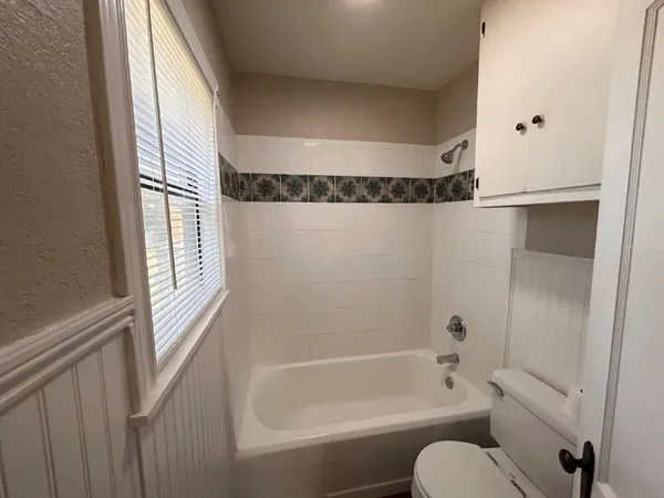 a bathroom with a granite countertop bathtub shower and a toilet