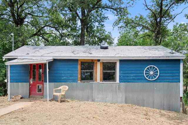 a view of a house with a yard chairs and wooden fence