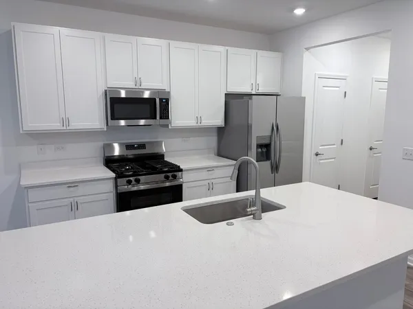 a kitchen with granite countertop a refrigerator sink and white cabinets