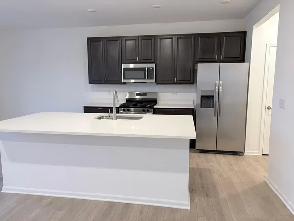 a kitchen with a sink a microwave a refrigerator and cabinets