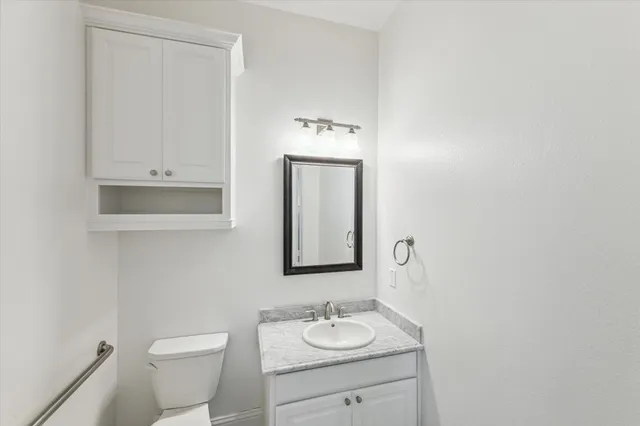 a bathroom with a granite countertop sink vanity mirror and toilet