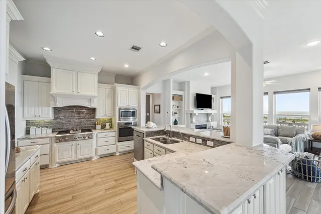 a large kitchen with stainless steel appliances kitchen island granite countertop a stove and a sink